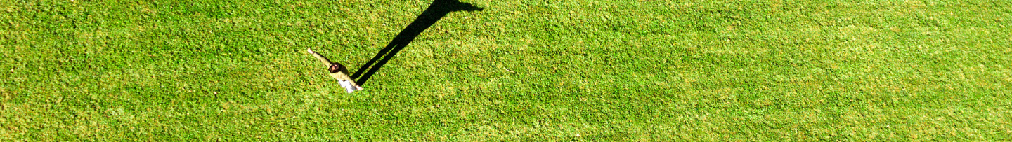 Een mevrouw in een heel groen grasveld van boven